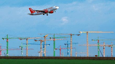 Hochfliegende Pläne. Ein Passagierflugzeug über den Kränen der größten Flughafenbaustelle Europas in Schönefeld. Der neue Flughafen BBI soll 2,2 Milliarden Euro kosten und 2011 in Betrieb gehen.