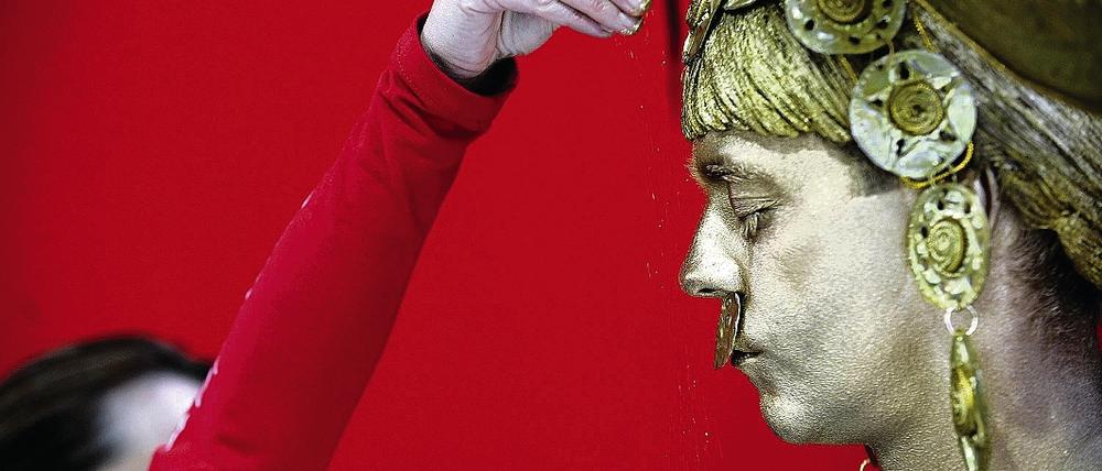 Träume von der Ferne. Am Messestand von Kolumbien bestreut eine Mitarbeiterin am Mittwoch den Darsteller der mythischen Figur El Dorado mit Goldstaub.
