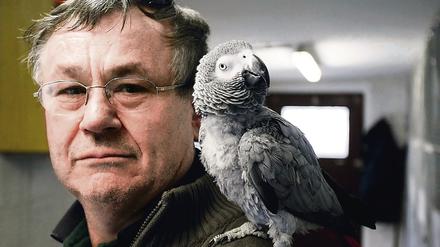 Hans-Jürgen Fengler posiert mit dem Graupapagei Julchen auf der Schulter.