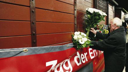 Zweite Tour. Der Überlebende der Kinderdeportationen durch das nationalsozialistische Regime, Zenon Bujonowski aus Polen, steckt Blumen an den Zug der Erinnerung. Das Projekt ist zum zweiten Mal unterwegs durch europäische Städte.