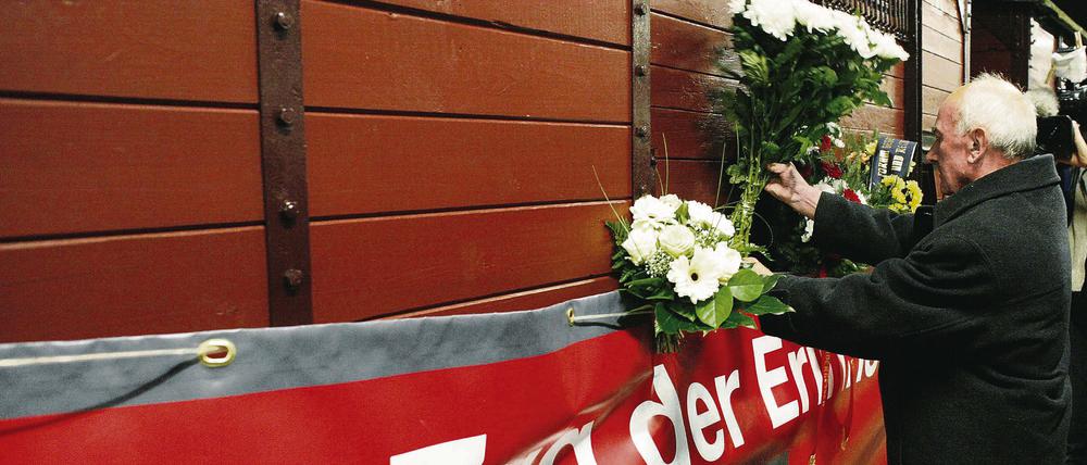 Zweite Tour. Der Überlebende der Kinderdeportationen durch das nationalsozialistische Regime, Zenon Bujonowski aus Polen, steckt Blumen an den Zug der Erinnerung. Das Projekt ist zum zweiten Mal unterwegs durch europäische Städte.