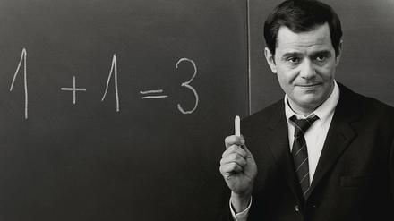 Weiß auf Schwarz. Pauker Walter Giller zeigt im Film Klassenkeile von 1969, wies geht. Mit dem Rechnen und mit dem Schreiben auf der guten alten Kreidetafel.