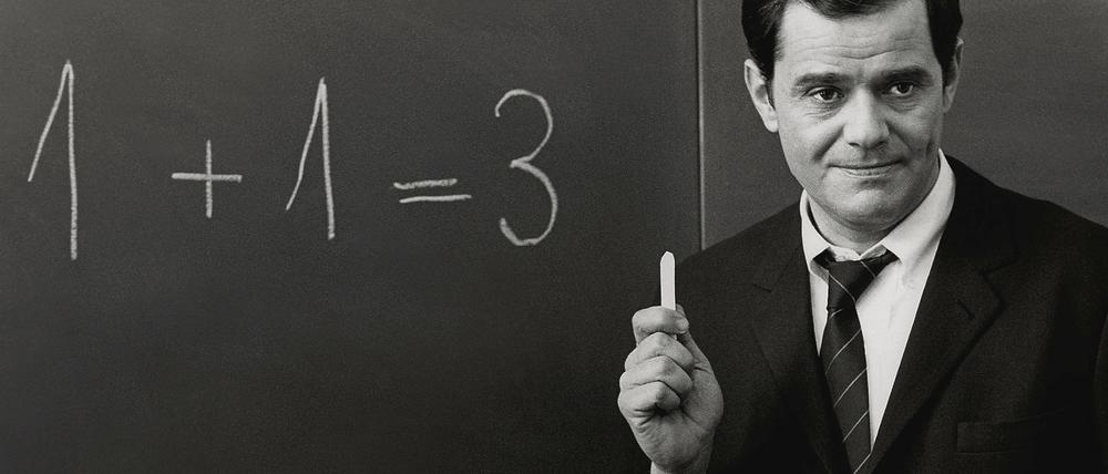 Weiß auf Schwarz. Pauker Walter Giller zeigt im Film Klassenkeile von 1969, wies geht. Mit dem Rechnen und mit dem Schreiben auf der guten alten Kreidetafel.