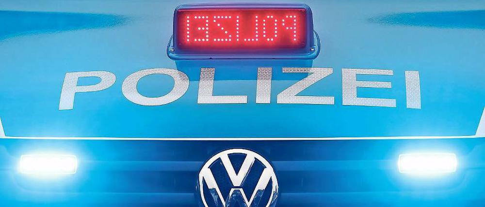 Ein Polizeiauto fährt mit angeschalteten Scheinwerfern.