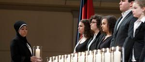 Eine junge Frau trägt am Donnerstag (23.02.12) im Konzerthaus in Berlin bei der zentralen Gedenkveranstaltung fuer die Opfer der Mordserie der terroristischen Vereinigung "Nationalsozialistischer Untergrund" (NSU) eine Kerze.