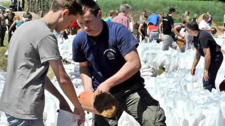 Kampf gegen die Flut: Freiwillige befüllen an der Elbe in der Prignitz Sandsäcke - anderenorts stören Gaffer die Einsatzkräfte und gefährden die Deiche.