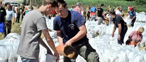 Kampf gegen die Flut: Freiwillige befüllen an der Elbe in der Prignitz Sandsäcke - anderenorts stören Gaffer die Einsatzkräfte und gefährden die Deiche.