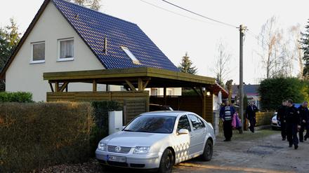 Polizisten gehen am Sonntag (25.03.12) in Brieslang vor einem Haus, in dem eine Frau erstochen wurde.
