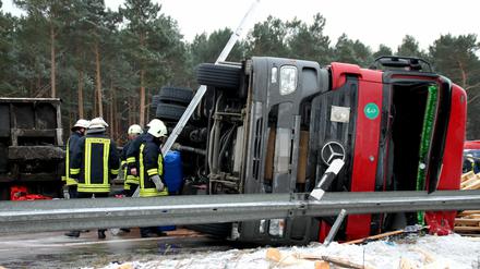 Feuerwehrleute begutachten am 21.01.2013 nach einem Unfall auf der A9 bei Niemegk (Brandenburg) den umgekippten LKW. Der Fahrer verlor die Kontrolle über seinen Lastwagen, der daraufhin zwischen den Anschlussstellen Brück und Niemegk (Potsdam-Mittelmark) auf die Mittelleitplanke kippte. Ein Teil der geladenen Paletten rutschte auf die Gegenfahrbahn, so dass die Autobahn seit dem Vormittag voll gesperrt ist.