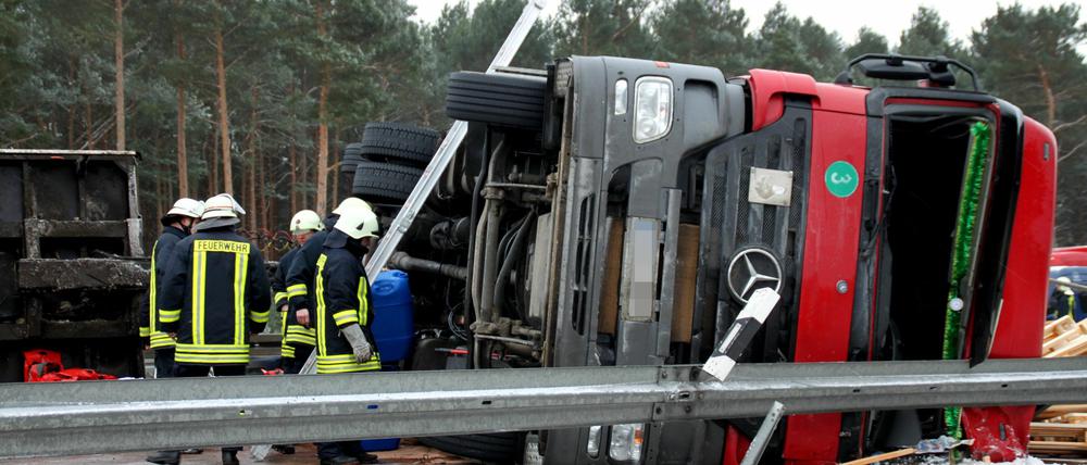 Feuerwehrleute begutachten am 21.01.2013 nach einem Unfall auf der A9 bei Niemegk (Brandenburg) den umgekippten LKW. Der Fahrer verlor die Kontrolle über seinen Lastwagen, der daraufhin zwischen den Anschlussstellen Brück und Niemegk (Potsdam-Mittelmark) auf die Mittelleitplanke kippte. Ein Teil der geladenen Paletten rutschte auf die Gegenfahrbahn, so dass die Autobahn seit dem Vormittag voll gesperrt ist.