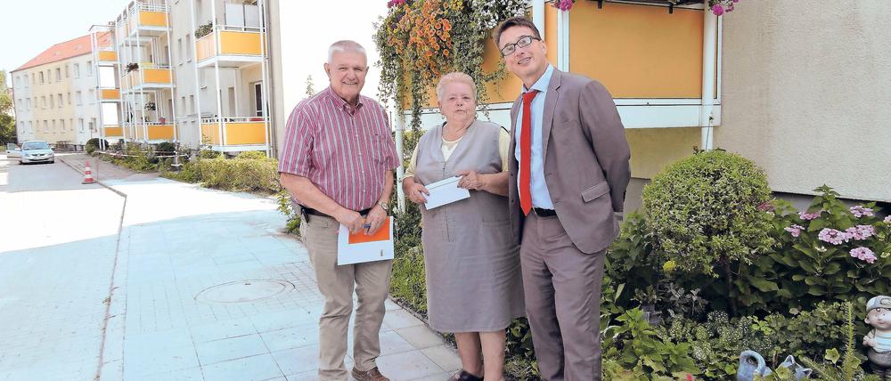 Selbst begrünt. Jutta Rochlitz hat von Hermann Bobka (l.) und Thomas Lück einen Scheck über 100 Euro erhalten. Sie hatte Blumen gekauft und vor dem Wohnblock gepflanzt.