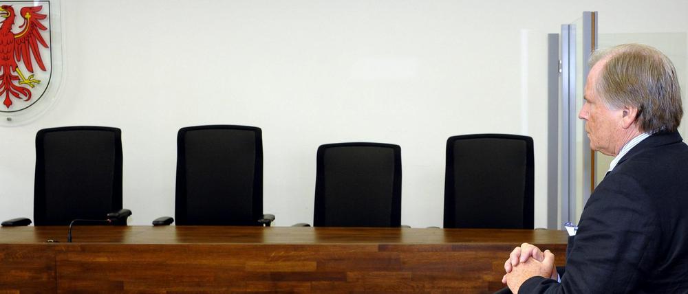 Der ehemalige Justizminister des Landes Brandenburg, Kurt Schelter (CDU), wartet am Montag (26.03.12) in einem Saal des Landgerichts in Potsdam auf die Fortsetzung des Betrugsprozesses gegen ihn, waehrend hinter der Richterbank das Wappen des Landes Brandenburg zu sehen ist. Dem ehemaligen Brandenburger Minister wird vorgeworfen, nach seinem Rücktritt 2002 Übergangsgeld sowie Ruhegehalt in Höhe von rund 100.000 Euro erschlichen zu haben.