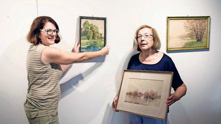 Teamarbeit. Carola Pauly (l.) und Jelena Jamaikina (r.) hängen die letzten Bilder für die Jubiläumsausstellung auf. Im Museumsverein packt jeder gern mit an.