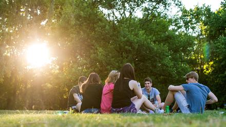 Jugendliche sitzen in den letzten Sonnenstrahlen am Tiergarten. 