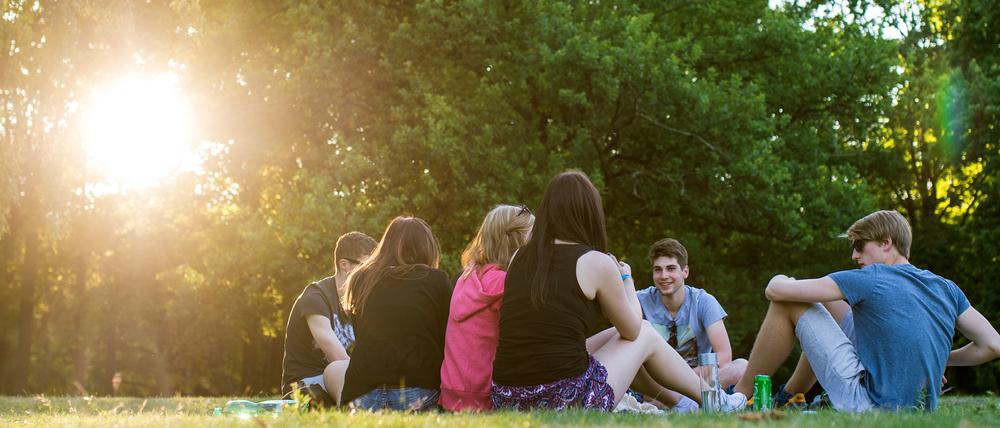 Jugendliche sitzen in den letzten Sonnenstrahlen am Tiergarten.