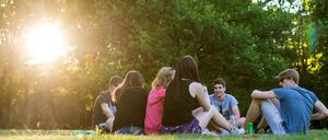 Jugendliche sitzen in den letzten Sonnenstrahlen am Tiergarten.