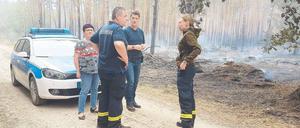 Spurensuche. Kommissar Frank Tiews (Mitte) lässt sich von den Feuerwehrleuten Olaf Fetz und Ulrike Fischer zeigen, wo der Brand hinter Frohnsdorf ausbrach.