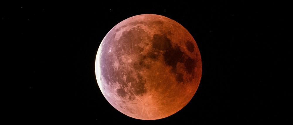 Der teilweise vom Erdschatten verdunkelte Vollmond leuchtet während einer Mondfinsternis rot bis orange.
