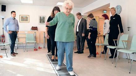 Mithilfe einer sogenannten Koordinationsleiter wird im Stahnsdorfer Seniorentreff Bewegungssicherheit eingeübt. Auch Bürgermeister Bernd Albers (BfB, 3.v.l.) probierte sich am Freitag darin aus.