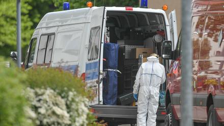 Eine Kriminaltechnikerin steht an ihrem Dienstfahrzeugvor dem mutmaßlichen Tatort in Forst.