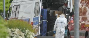 Eine Kriminaltechnikerin steht an ihrem Dienstfahrzeugvor dem mutmaßlichen Tatort in Forst.