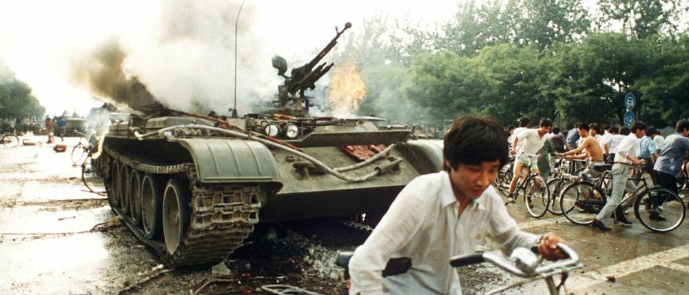 Menschen fliehen vor 30 Jahren vor einem in Brand gesetzten Panzer westlich des Tien An Men-Platzes in Peking.