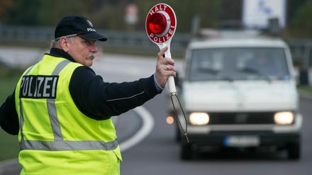 Ein Polizeibeamter winkt mit einer Kelle zu einer Verkehrskontrolle.