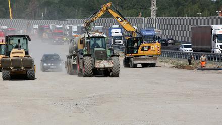 Traktoren verteilen Wasser auf der Baustelle der A10 bei Michendorf, damit es nicht so staubt.