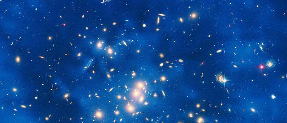 Was die Welt zusammenhält. Der Nachweis von schweren Gravitinos wäre ein wichtiger Schritt zur allenthalben gesuchten vereinheitlichten Theorie der Physik. Die Dunkle Materie, die aus diesen Teilchen bestehen könnte, macht sich nur über Gravitationseffekte bemerkbar. Die Aufnahme zeigt einen Ring Dunkler Materie in einem fünf Milliarden Lichtjahre entfernten Galaxienhaufen im Sternbild Fische.