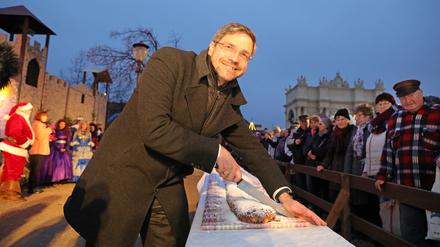 Oberbürgermeister Mike Schubert (SPD) schneidet traditionell den Weihnachtsstollen für die Besucher an.