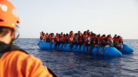 Ein Seenotretter schaut zu einem Flüchtlingsboot. 