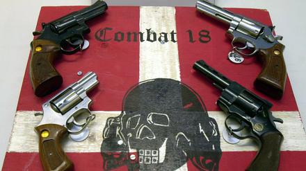 Sichergestellte Waffen und ein Schild der kriminellen Neonazi-Gruppe "Combat 18" (Archivbild).