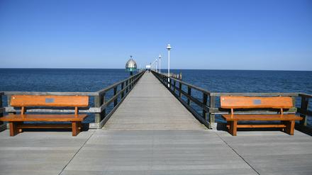 05.04.2020, Mecklenburg-Vorpommern, Zinnowitz: Zwei Spaziergänger gehen auf der Seebrücke im Ostseebad Zinnowitz auf der Insel Usedom. Wegen der scharfen Einschränkungen im öffentlichen Leben wird der traditionelle Saisonauftakt an der Ostsee zu Ostern in diesem Jahr ausfallen. Foto: Stefan Sauer/dpa +++ dpa-Bildfunk +++