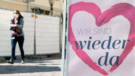 Eine Frau mit Mundschutz geht vor der Tür einer Parfümerie in der Einkaufsmeile Brandenburger Straße vorbei.