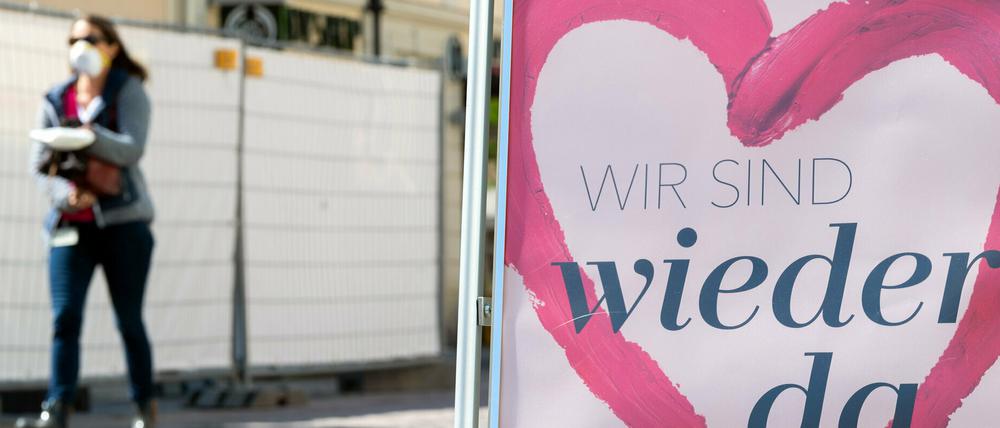 Eine Frau mit Mundschutz geht vor der Tür einer Parfümerie in der Einkaufsmeile Brandenburger Straße vorbei.