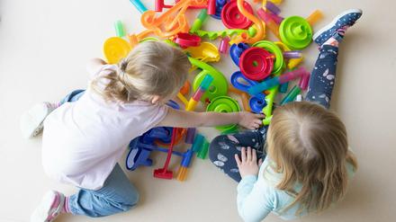 Zwei Kinder spielen in einem Kindergarten auf dem Fußboden.