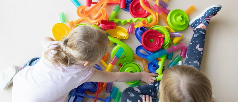 Zwei Kinder spielen in einem Kindergarten auf dem Fußboden.