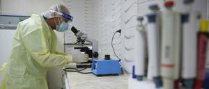 Ein Arzt in Schutzkleidung sieht durch ein medizinisches Teleskop (Symbolbild).