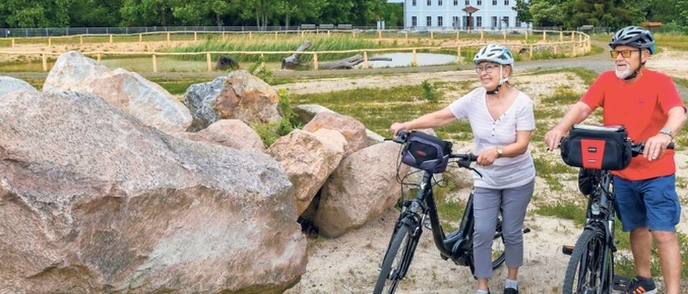 Die Urlauber Uta Trost und Andreas Schuster stehen mit ihren Fahrrädern neben Findlingen am rekultivierten Geisendorfer Berg.