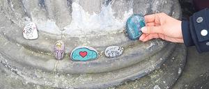 Wanderkiesel an Schlosssäulen. Bunt bemalte Steine werden von Mitgliedern einer Facebook-Gruppe in ganz Potsdam verteilt.