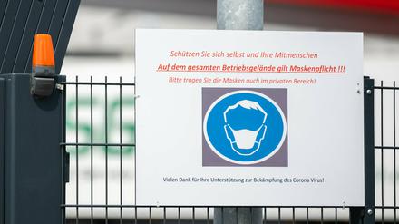 Ein Schild vor einem Schlachthof weist auf die Maskenpflicht hin. 