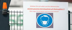 Ein Schild vor einem Schlachthof weist auf die Maskenpflicht hin. 