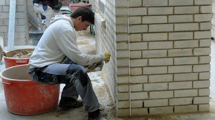 Lehrlinge arbeiten in einem Bildungs- und Technologiezentrum der Handwerkskammer an einem Mauerwerk.