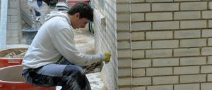 Lehrlinge arbeiten in einem Bildungs- und Technologiezentrum der Handwerkskammer an einem Mauerwerk.