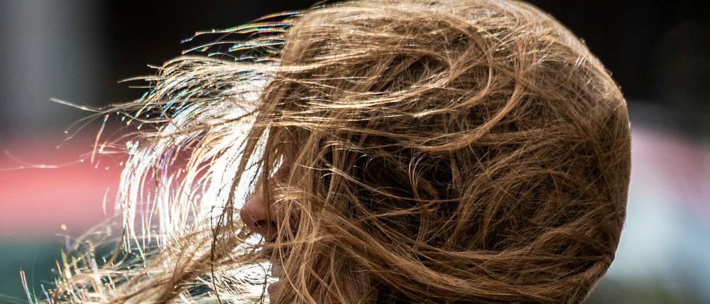 Sturmtief "Kirsten" lässt dieser Frau bei ihrem Weg durch in der Innenstadt die Haare ins Gesicht wehen.