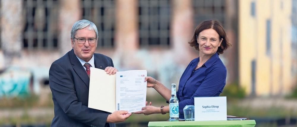 Geldübergabe vor Ruinen. Wirtschaftsminister Jörg Steinbach (SPD) übergab den Fördermittelbescheid auf dem Ex-Kasernenareal an Stadtwerke-Chefin Sophia Eltrop.