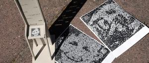 Modell: Große Stühle werfen Texte als Schatten auf den Boden des Platzes.