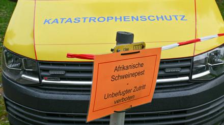 29.09.2020, Brandenburg, Neuzelle: Ein Zettel mit der Aufschrift «Afrikanische Schweinepest Unbefugter Zutritt verboten» hängt an einem Pfeiler vor einem Fahrzeug vom Katastrophenschutz.