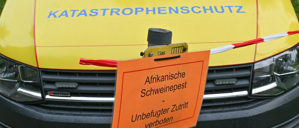 29.09.2020, Brandenburg, Neuzelle: Ein Zettel mit der Aufschrift «Afrikanische Schweinepest Unbefugter Zutritt verboten» hängt an einem Pfeiler vor einem Fahrzeug vom Katastrophenschutz.