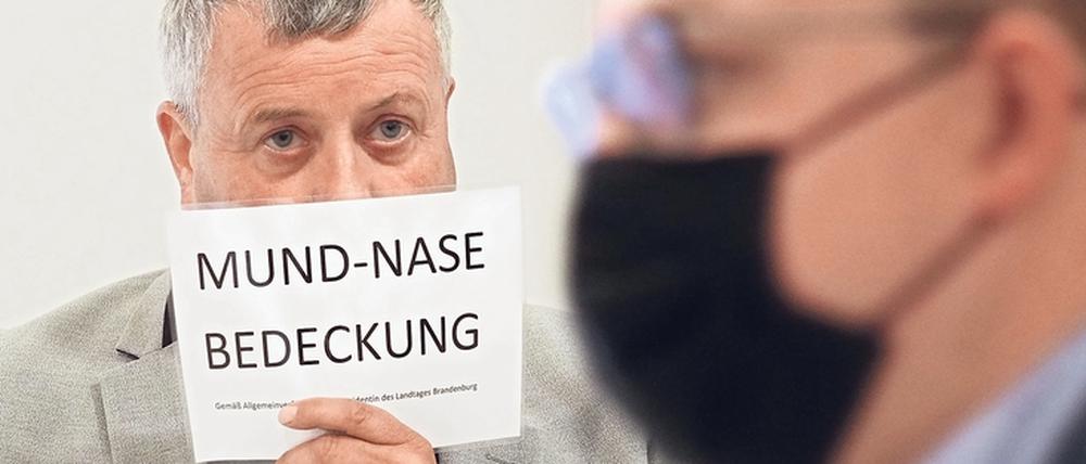Im Landtag, auch im Plenarsaal, gilt inzwischen Maskenpflicht. Der AfD-Abgeordnete Michael Hanko hält sich während einer Landtagssitzung ein Schild vors Gesicht. Die AfD zweifelt den Nutzen von Masken an.